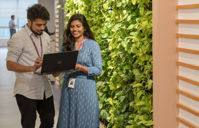 Two athenistas conversing with laptop in hand at Bangalore, India office